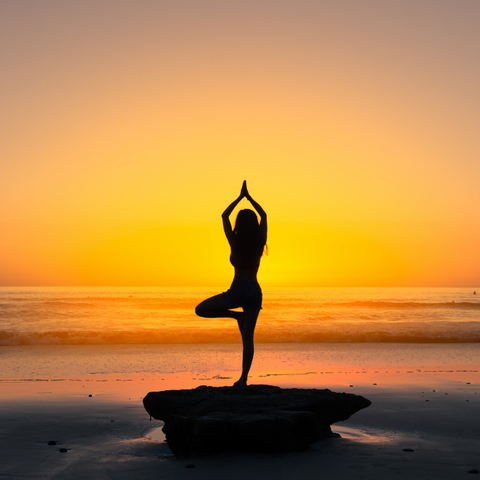 A woman doing yoga at sunset