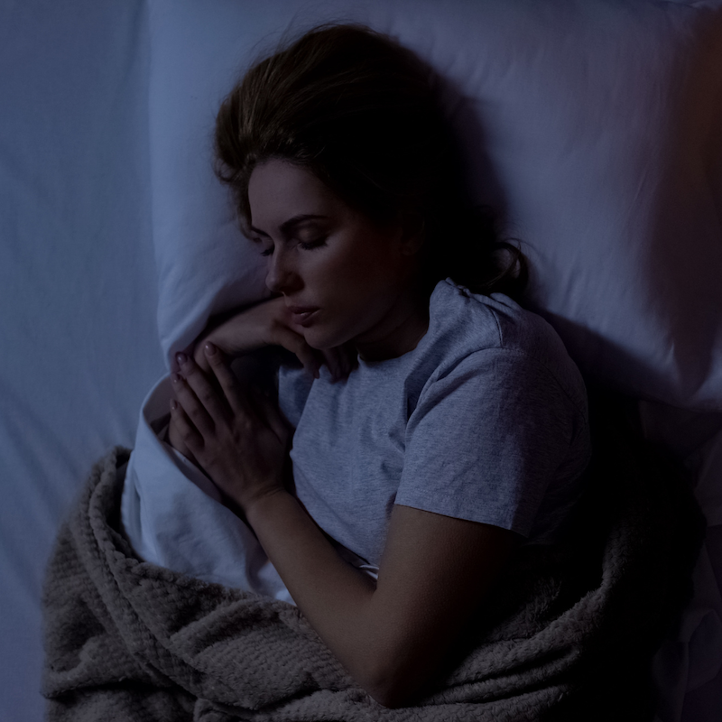 A woman sleeping in a dark, cozy room