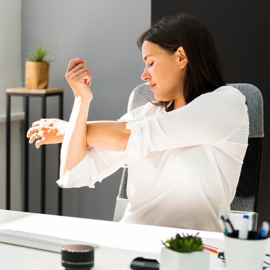 A woman sit-in at a desk stretching her upper body