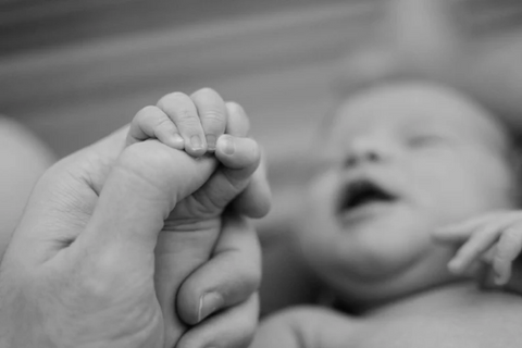 newborn baby hand wrapped arounds parent's finger