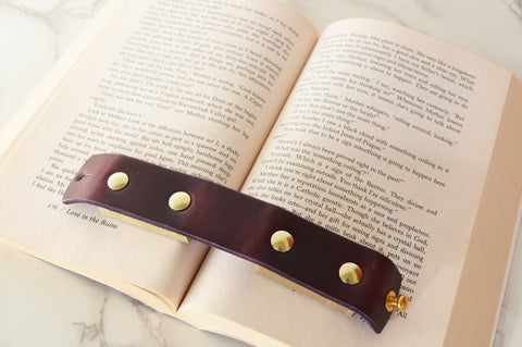 The Nomadic Book Weight in purple Horween leather with brass appointments