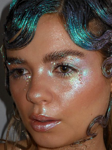 model wearing a very shimmery glitter all over the face with slicked hair
