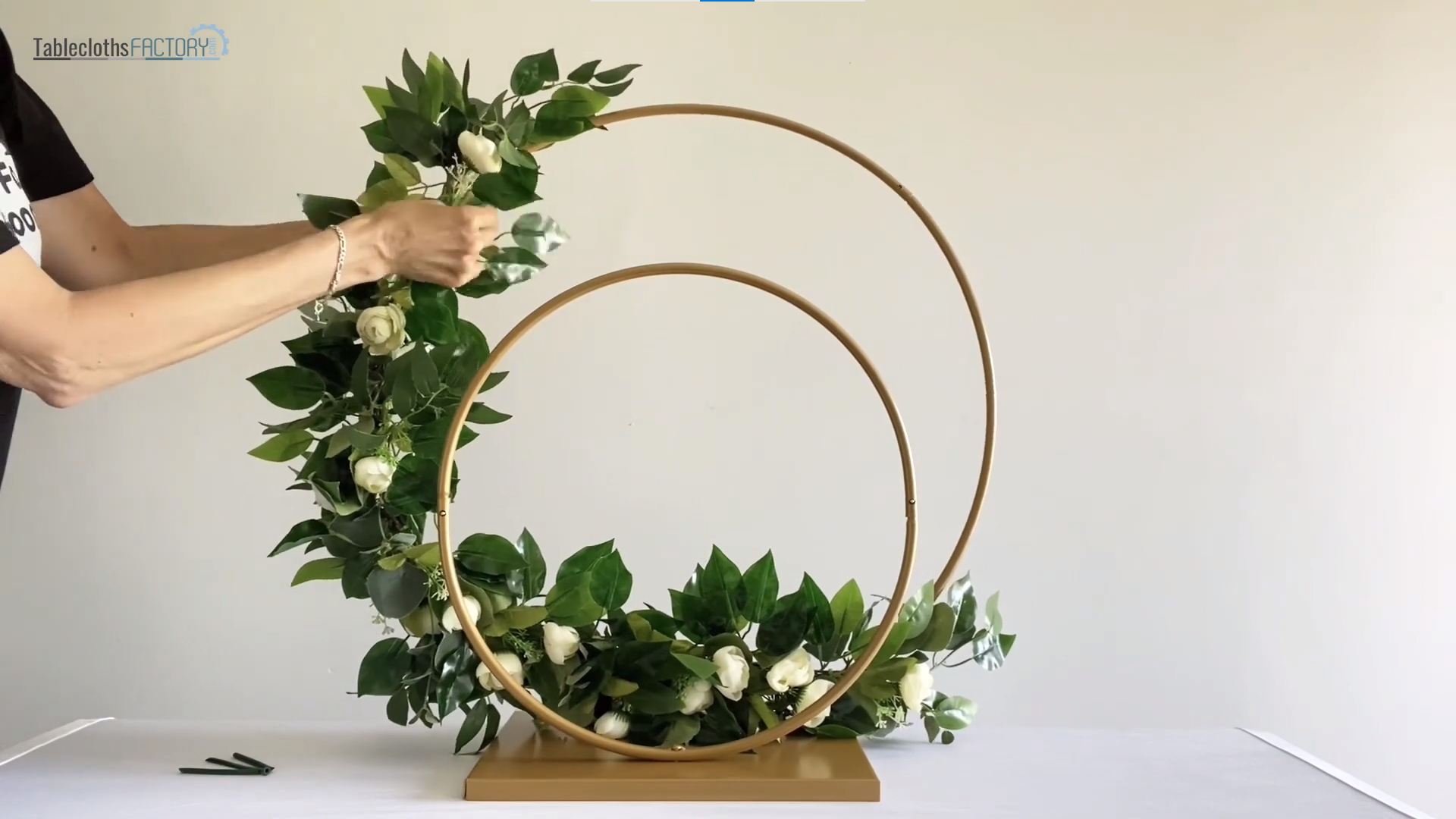 Person attaching a greenery to the hoop stand