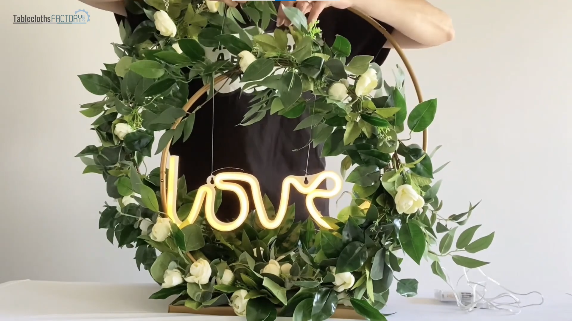 Person attaching a 'love' neon light sign to the hoop stand