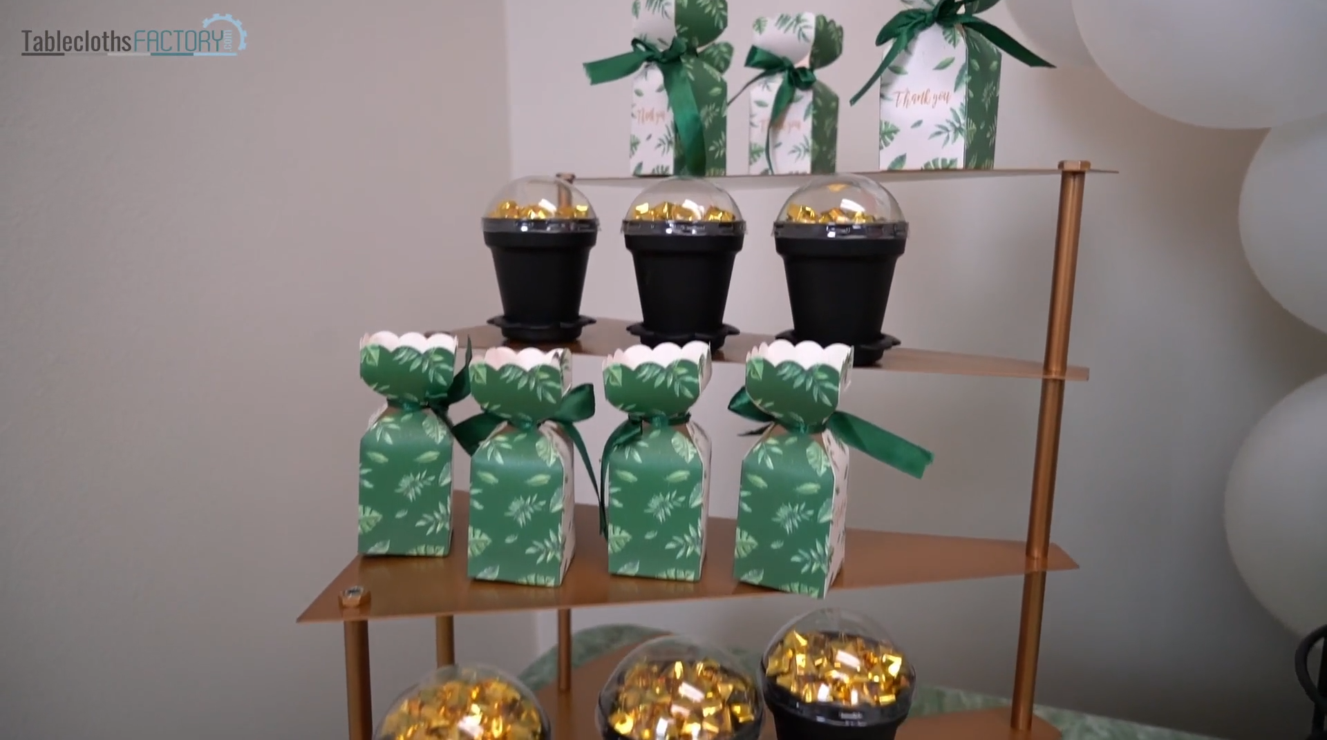 Green party favor boxes and black dessert cups on a tiered cupcake stand