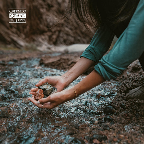 Foto de mão feminina jovem pegando pedras em rio
