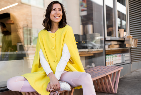 a woman in a Yellow Giulia Cape sitting in a bench in New York