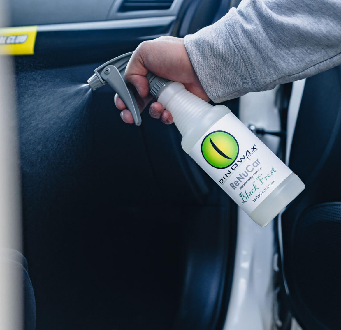 A person sprays a cleaning product inside a car.