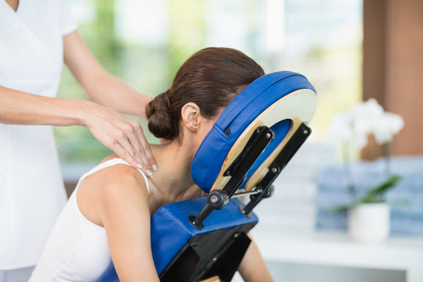 Woman receiving back massage with face in cradle to protect eyelash extensions. Cartel Lash