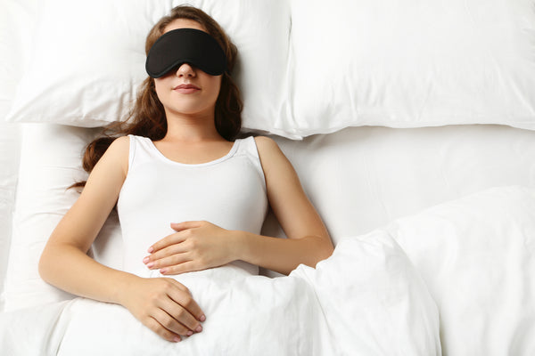 Young woman sleeping with 3D eye mask in white bed to protect eyelash extensions. Cartel Lash