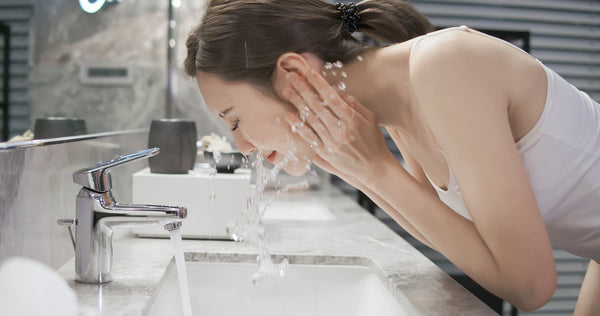Woman washing her face and lash extensions with water. Cartel Lash 