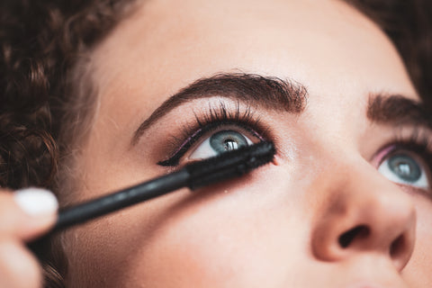 Woman wearing make up putting on specially formulated mascara for lash extensions. Cartel Lash
