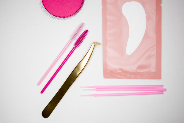 Tools in eyelash extension kit include golden tweezers, microbrush, and under eye patches. Cartel Lash