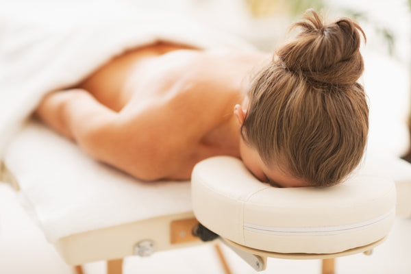 Young woman laying on massage table with eyelash extensions. Cartel Lash