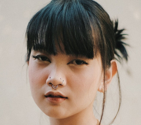 Young woman with high nostril piercings and golden septum ring jewelry