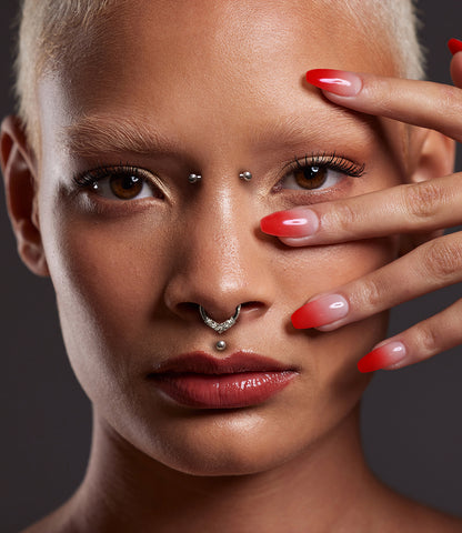 Young woman with long red nails and septum piercing with higher nostril studs