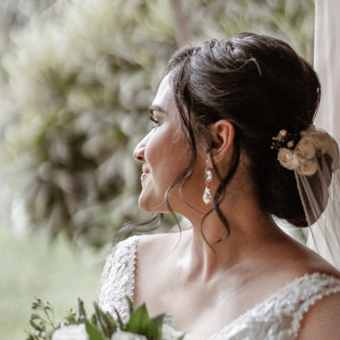 Image of a dark haired bride looking out of a doorway. She has her hair up and is wearing Leoni & Vonk baroque pearl and crystal earrings