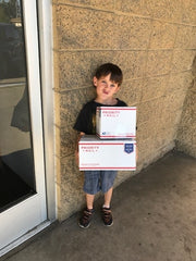 Boy holding USPS Priority shipping boxes, our first boxes of plant mail we shipped out.