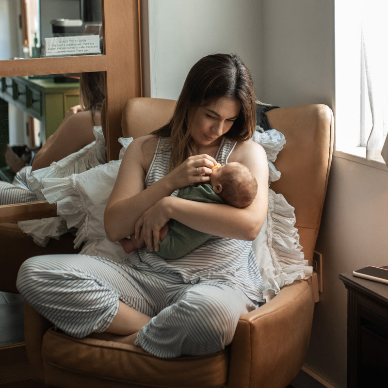 mother sitting on a chair holding a baby in her arms