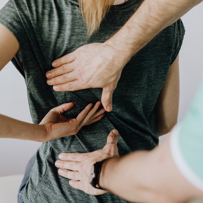 woman's hand holding lower back with man's hands reaching out