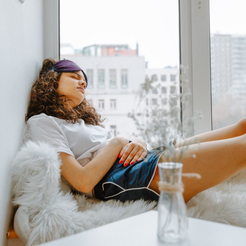 woman sat in window holding stomach