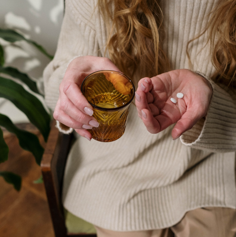 woman holding glass of water and two pills