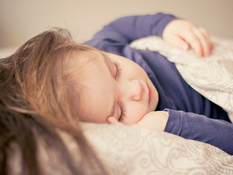 Jeune fille allongée dans son lit avec les couvertures sur elle.