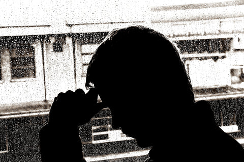 Man putting his hand on his forehead in black and white.