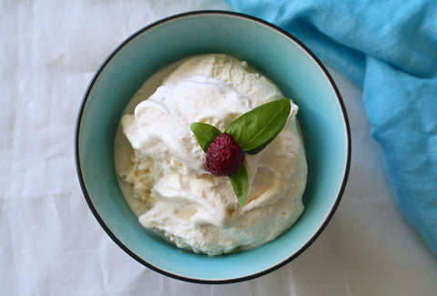 Bowl with ice cream, raspberry, and mint leaf.