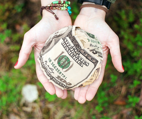 Two hands extended outward holding a clump of money.