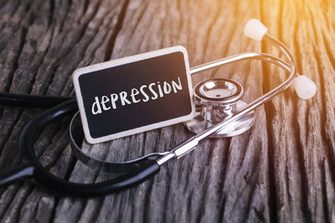 Stethoscope and card lying on a table with the word "depression" written on it.