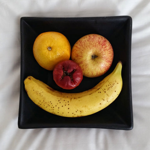 Fruit on a plate arranged in the shape of a smiley face