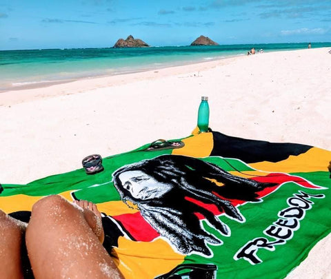Bob Marely Freedom Sarong or Pareo laid out on the beach with someone laying on it