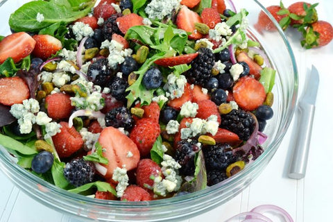 A bowl of leafy spinach, blackberries, sliced strawberries and more in a glass bowl next to our RADA Granny Paring knife