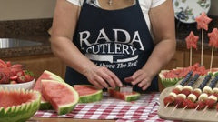 Kristi making star shapes from a large watermelon using a small metal cookie cutter