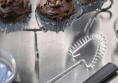 A RADA Handi-Stir next to a two chocolate muffin holder on top of a silver serving dish