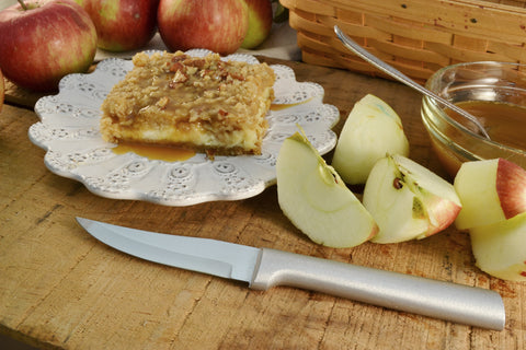 A RADA Heavy Duty Paring Knife in front of a handful of apple slices and a apple dessert bar on top of a white ceramic platter