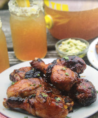 BBQ'd drumsticks in front of a mason jar of sweet tea and party dip