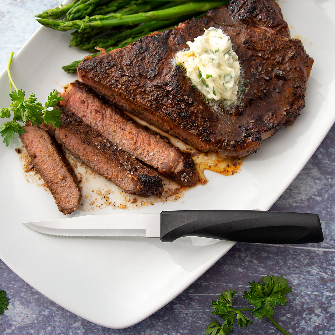 Rada Cutlery Anthem Wave Serrated Steak knife on plate with sliced steak. 