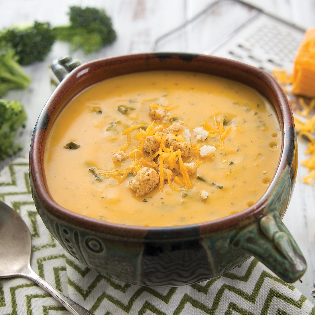 Cheddar Broccoli Soup in bowl garnished with cheese. 