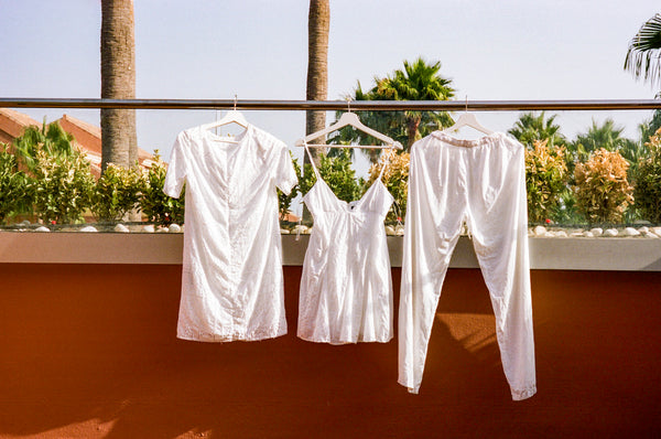 Three white items of clothing hanging against an orange wall.