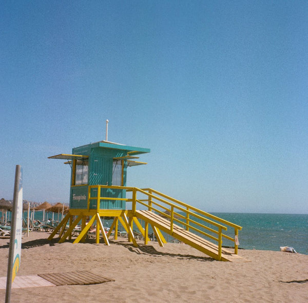 A brightly-coloured lifeguard post by the ocean.
