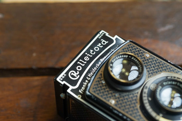 A Rolleicord TLR camera laying flat on a wooden box.