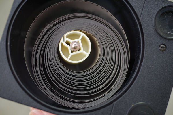 A bulk roll of 35mm film wrapped around the inside of a Kaiser Bulk Loader.