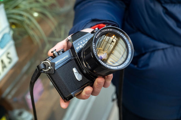 A black camera with a large lens being held by someone.