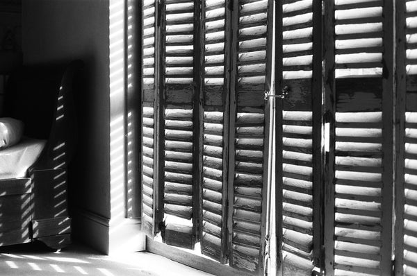 Light shining through shutter in black and white.