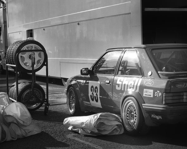 A vintage car in a repair bay in black and white.