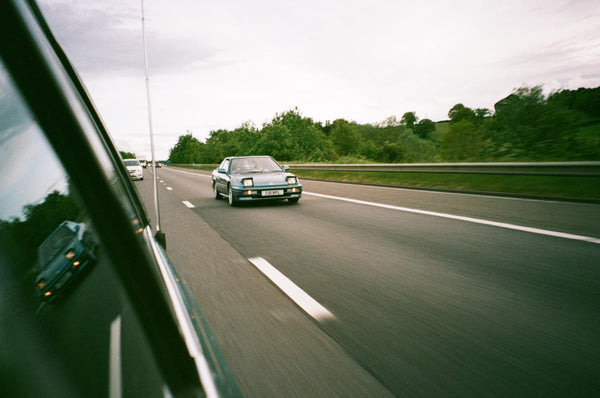 A vintage car speeding down the highway.