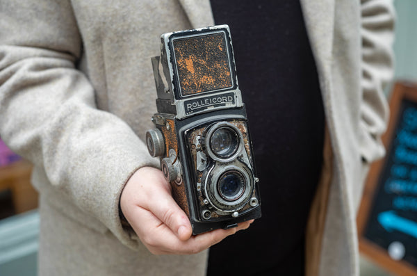 A person holding a vintage, battered old twin-lens-reflex camera.
