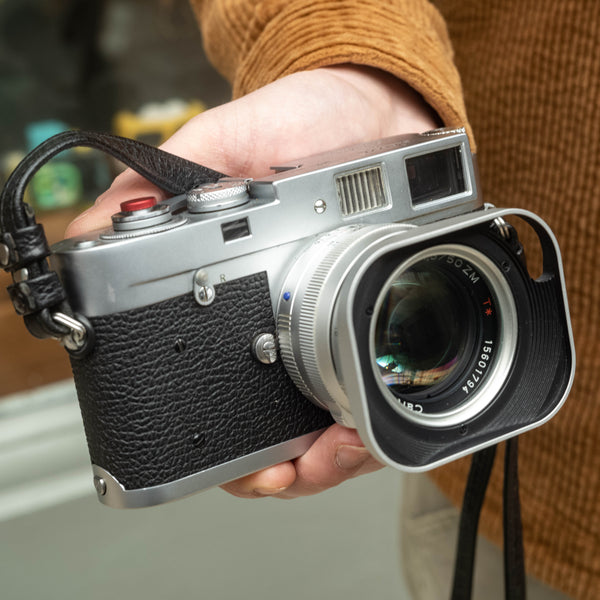 Leica M2 Camera with a 50mm f/1.5 Zeiss lens being held in front of a shop.